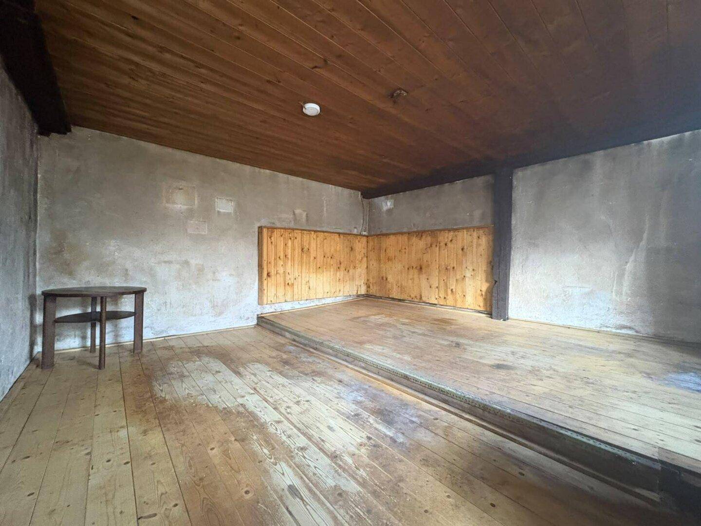 Geräumiger Kellerraum mit Holzdielenboden, Holzdecke und Holzwänden.