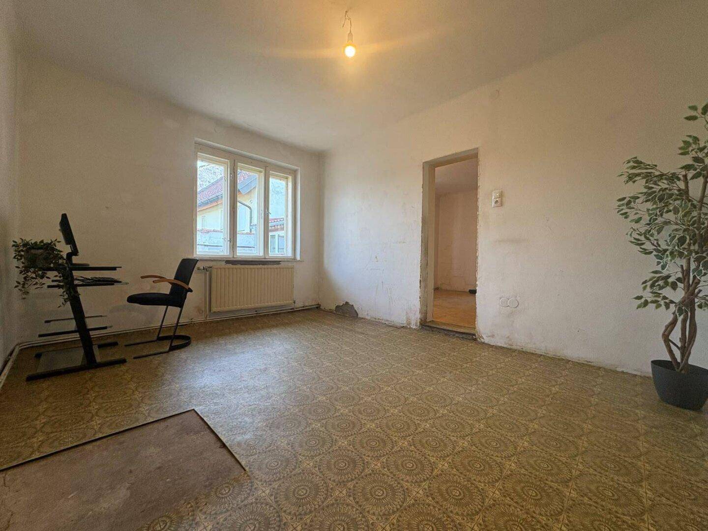 Zimmer mit gemustertem Boden, Fenster und Blick auf die Umgebung.