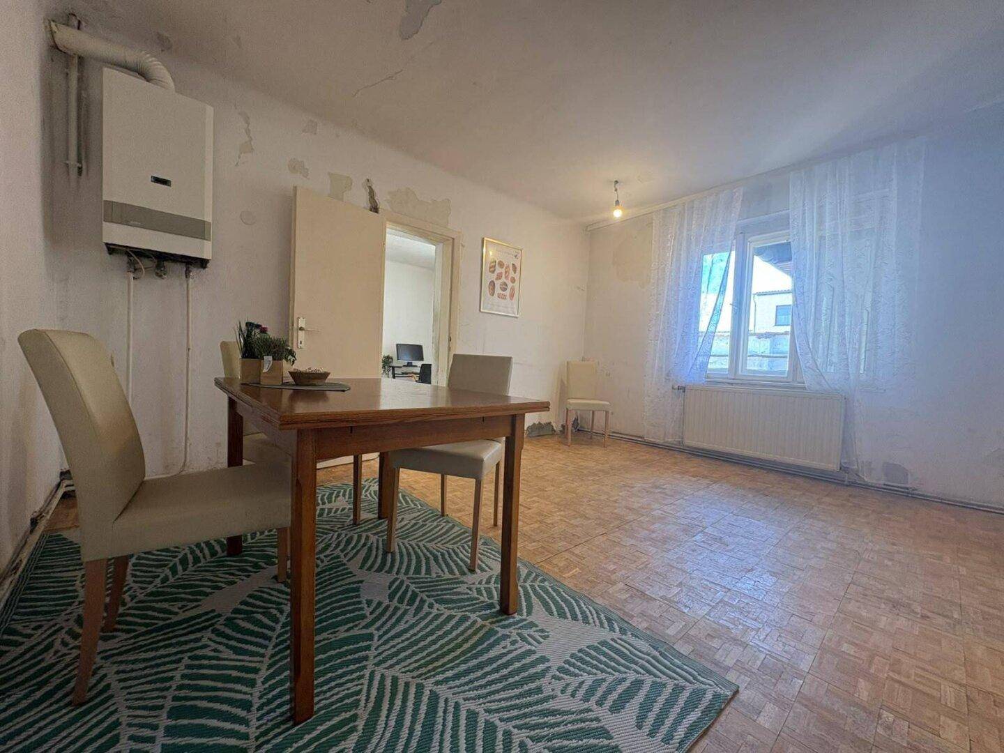 Esszimmer mit Holzboden, Esstisch und Heizungsanlage an der Wand.