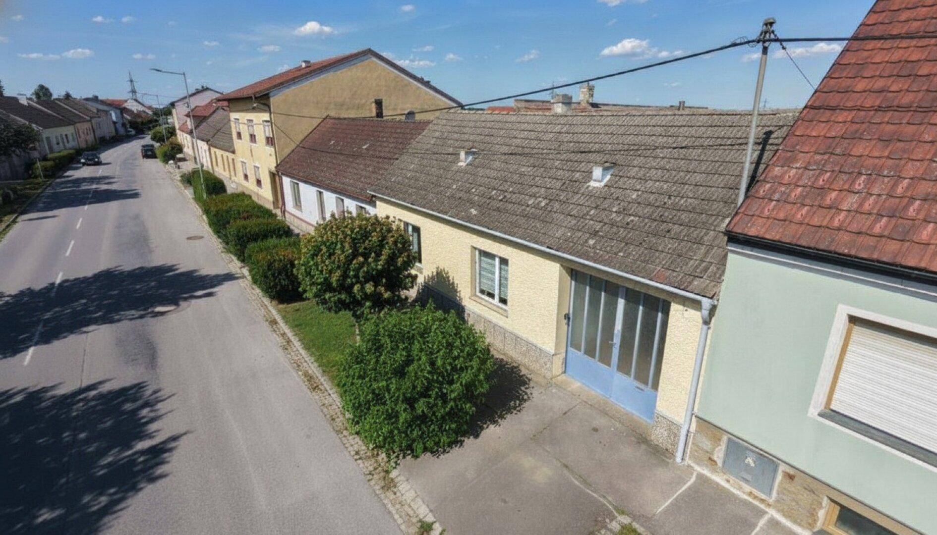 Luftaufnahme des Hauses mit Satteldach, Garten und der umliegenden Straße.