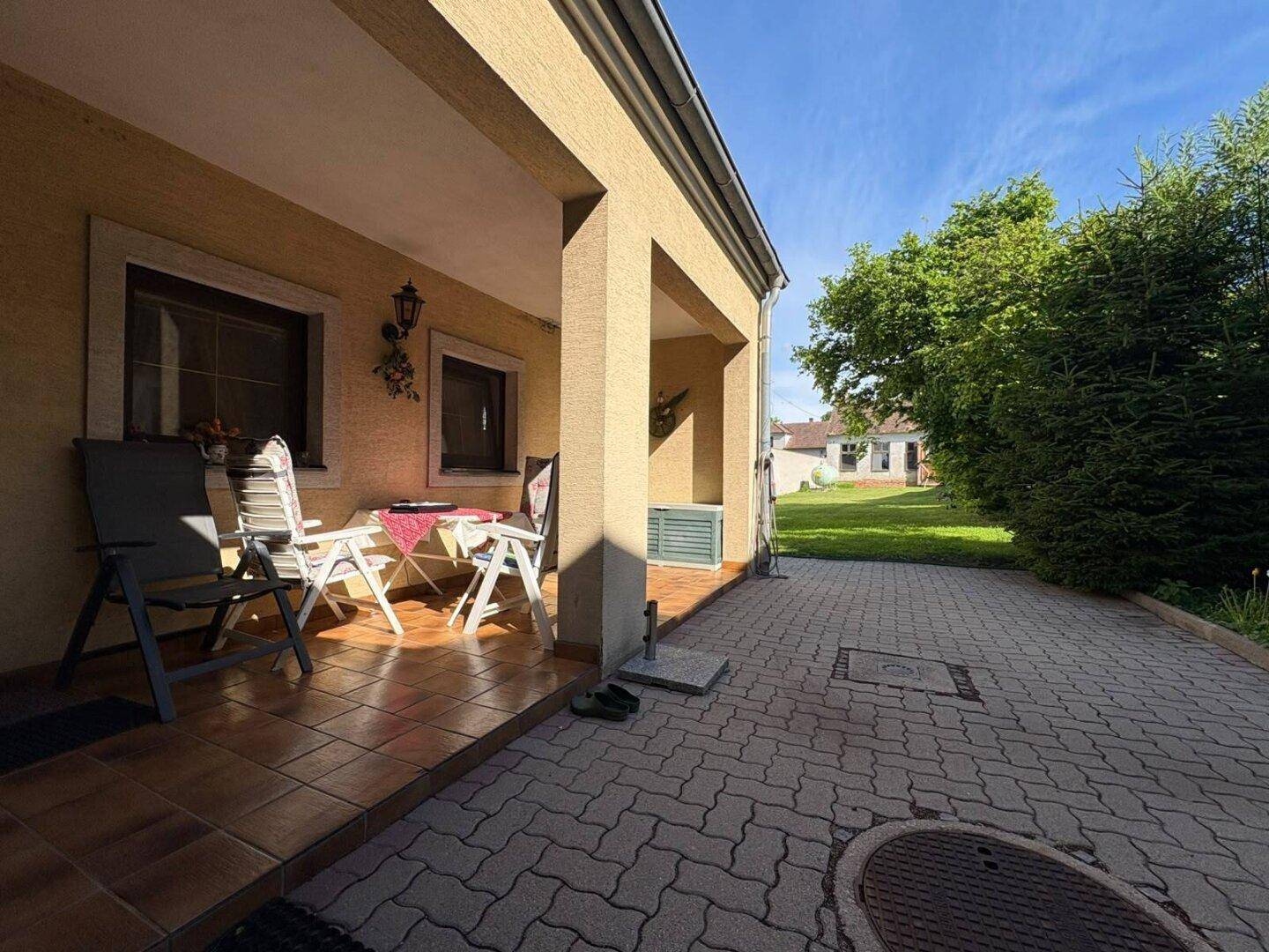 Überdachte Terrasse mit Sitzgelegenheiten und Blick auf den Garten, ideal für Entspannung.