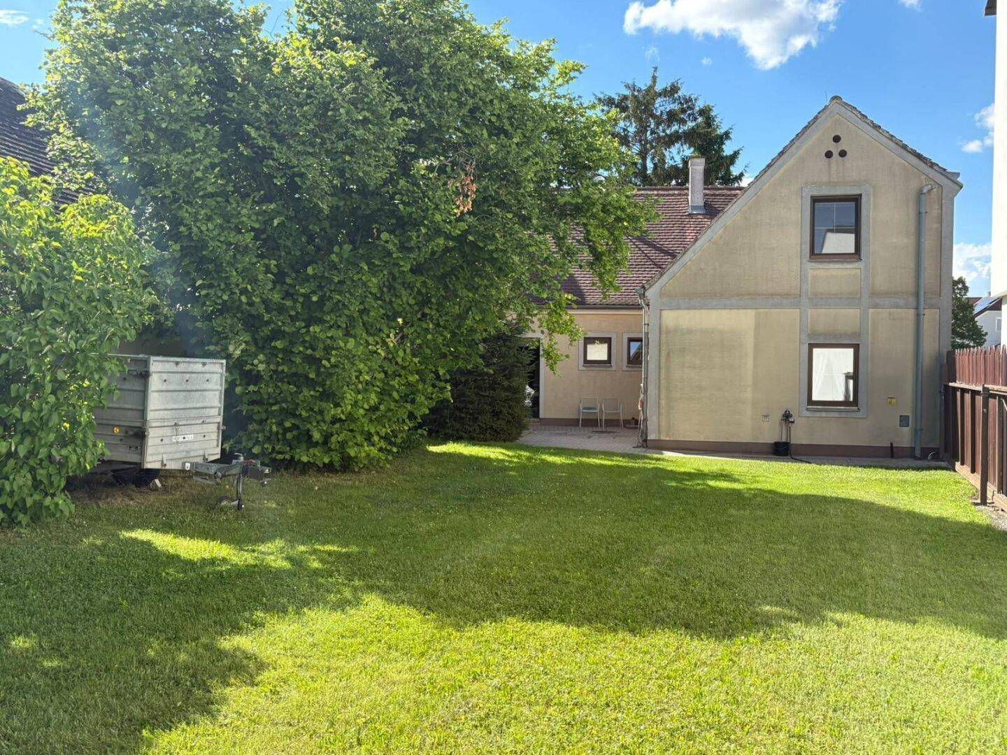 Weitläufiger Garten mit Rasenfläche und Bäumen, bietet viel Platz im Freien.