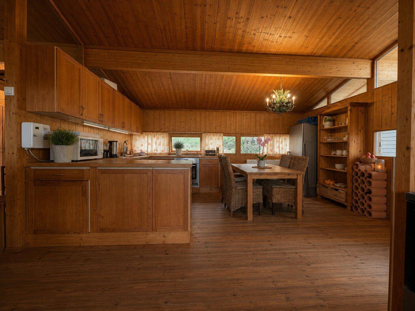 Geräumige Holzküche mit Essbereich, Einbaugeräten und viel natürlichem Licht.