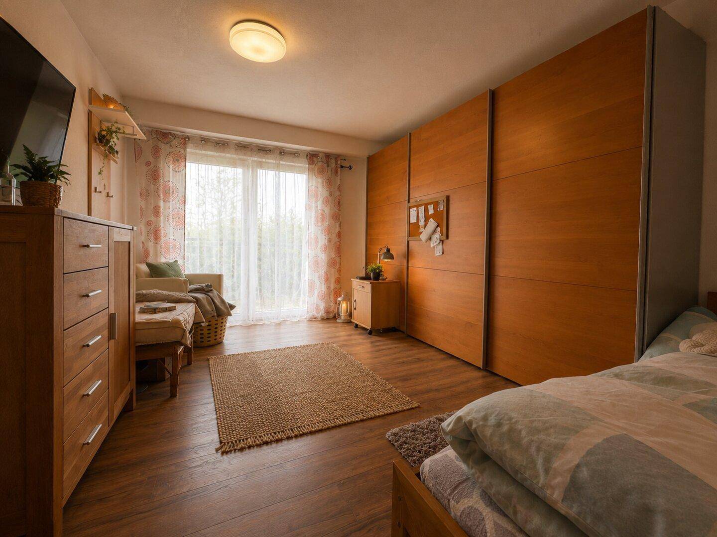 Geräumiges Schlafzimmer mit Holzboden, großen Schränken und Zugang zur Terrasse.
