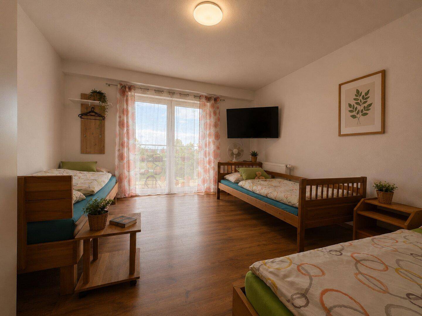 Helles Schlafzimmer mit mehreren Betten und Zugang zur Terrasse, ideal für Gäste.