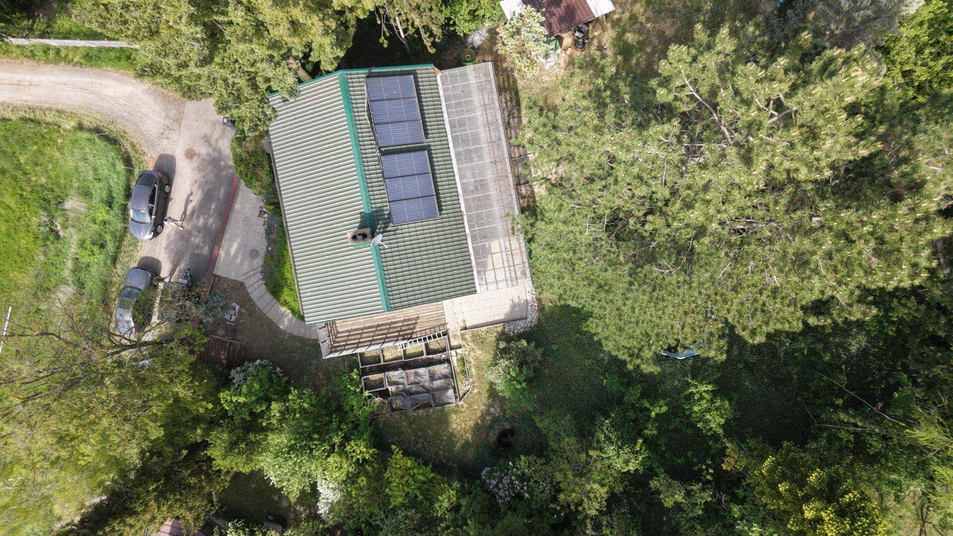 Luftaufnahme des Anwesens mit einem Haus, umgeben von Bäumen, einer Zufahrt und Solarpaneelen auf dem Dach.