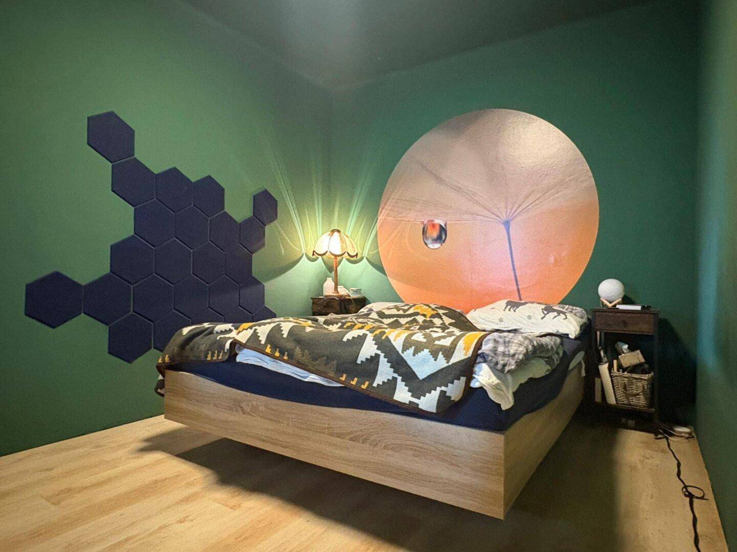 Schlafzimmer mit grünen Wänden, einem Holzbettrahmen und einer auffälligen Wanddekoration.