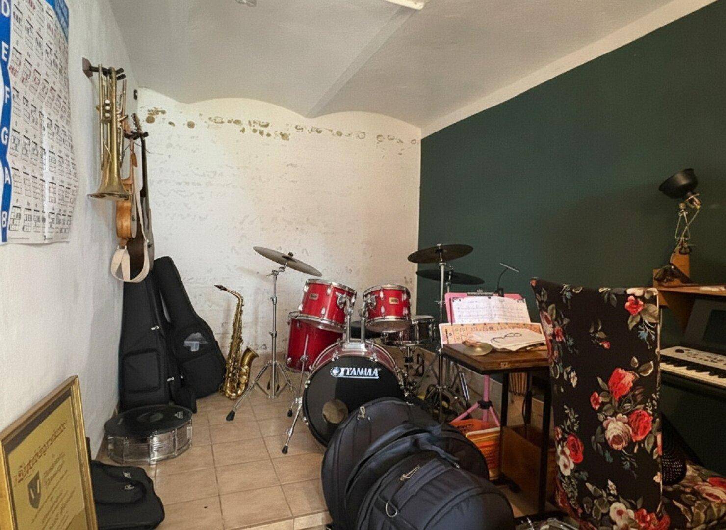 Musikzimmer mit Schlagzeug, Saxophon und anderen Instrumenten, ideal für kreative Entfaltung.