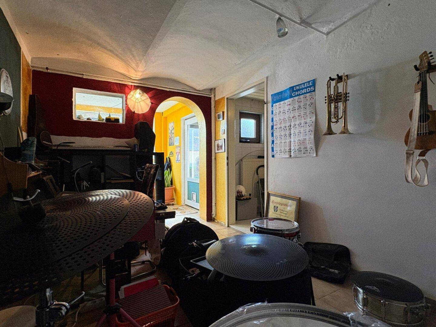 Musikzimmer mit Blick auf einen angrenzenden, gelb gestrichenen Bereich durch einen Rundbogen.