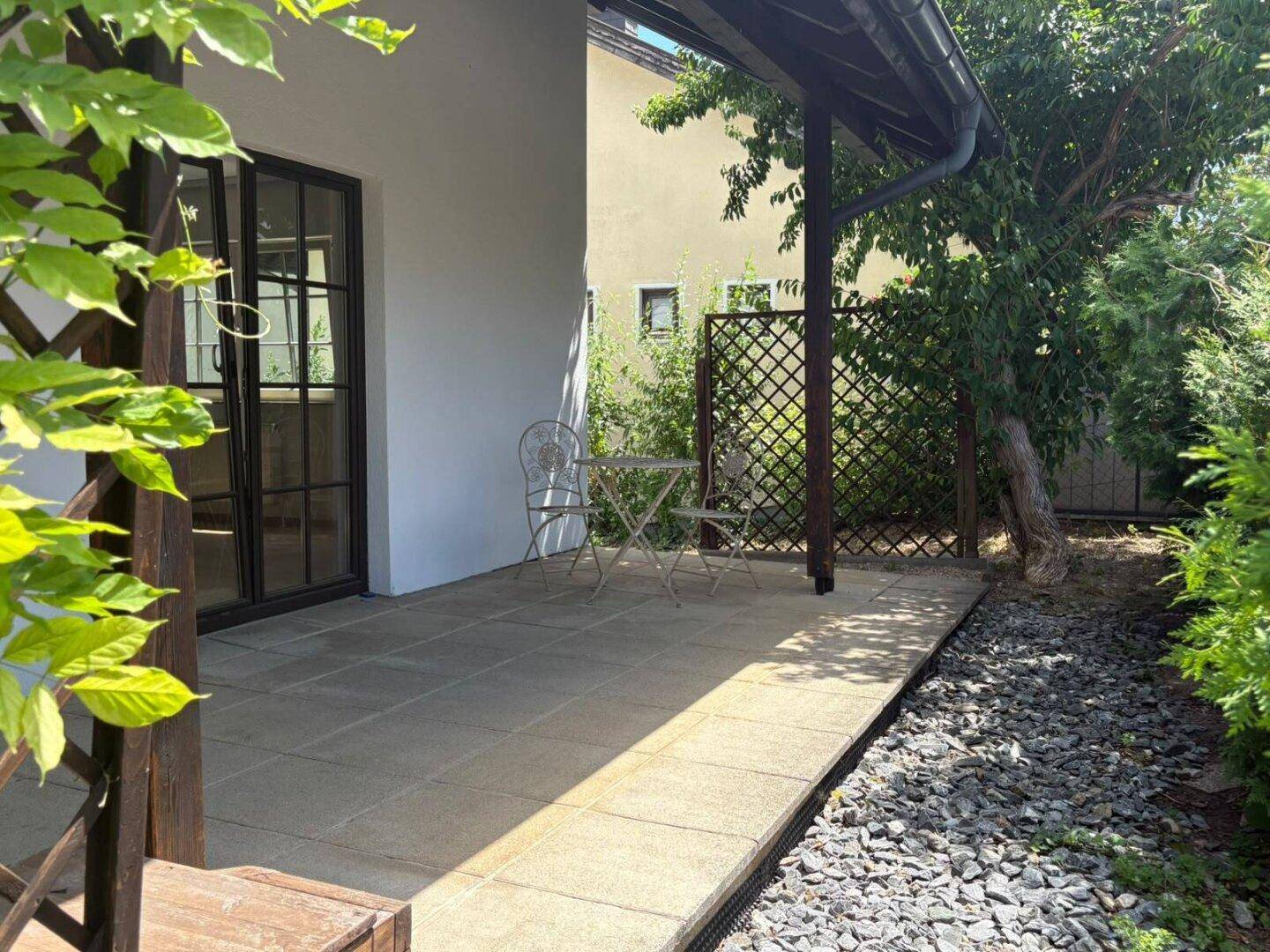 Gemütliche gepflasterte Terrasse mit Sitzgelegenheiten und Blick ins Grüne.