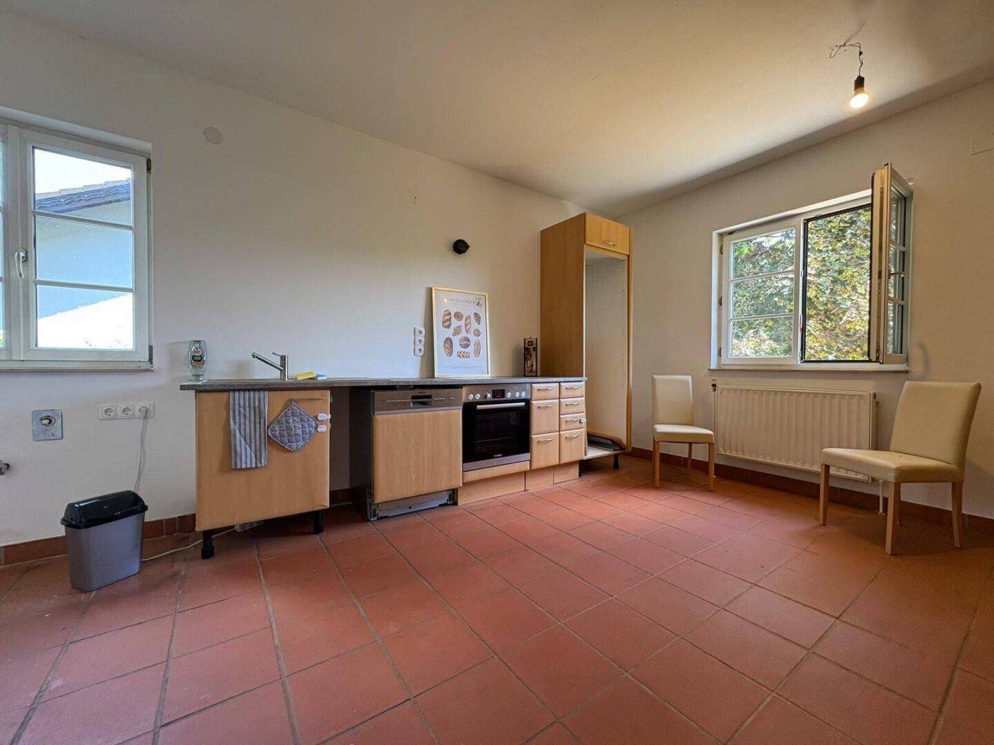 Geräumige Küche mit einfachen Einbaumöbeln, Spülmaschine und zwei Fenstern für viel Licht.