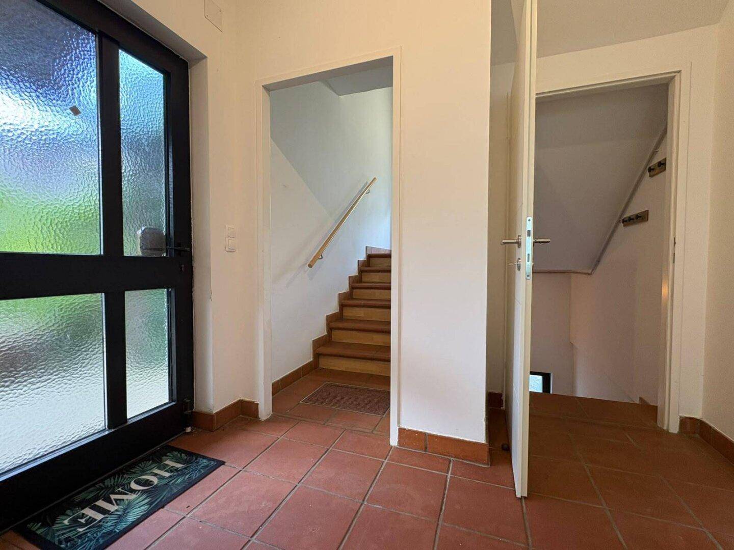 Eingangsbereich mit Haustür und Treppe, die in die oberen Stockwerke führt.