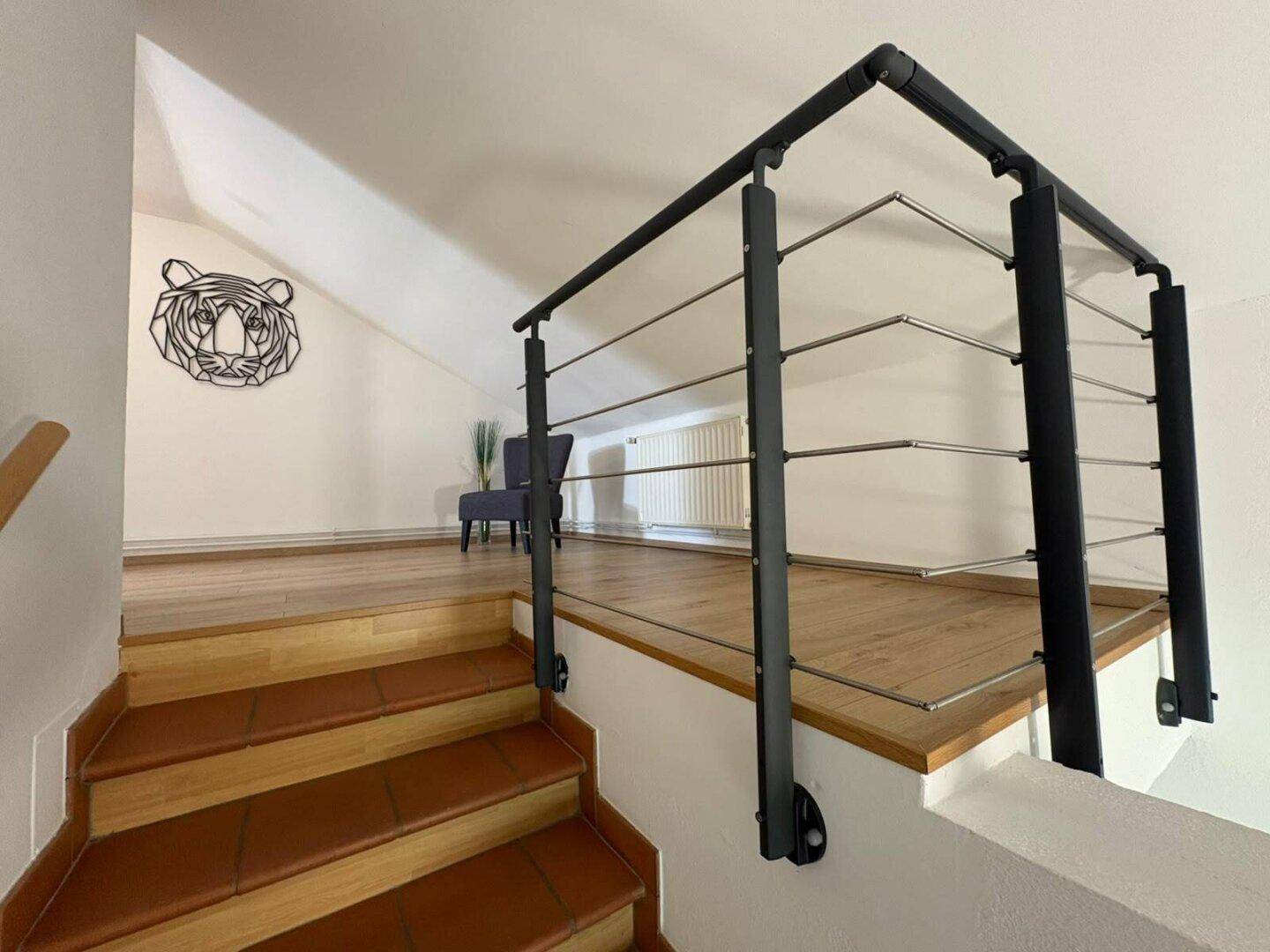 Offener Treppenabsatz im Dachgeschoss mit modernem Geländer und schrägen Decken.