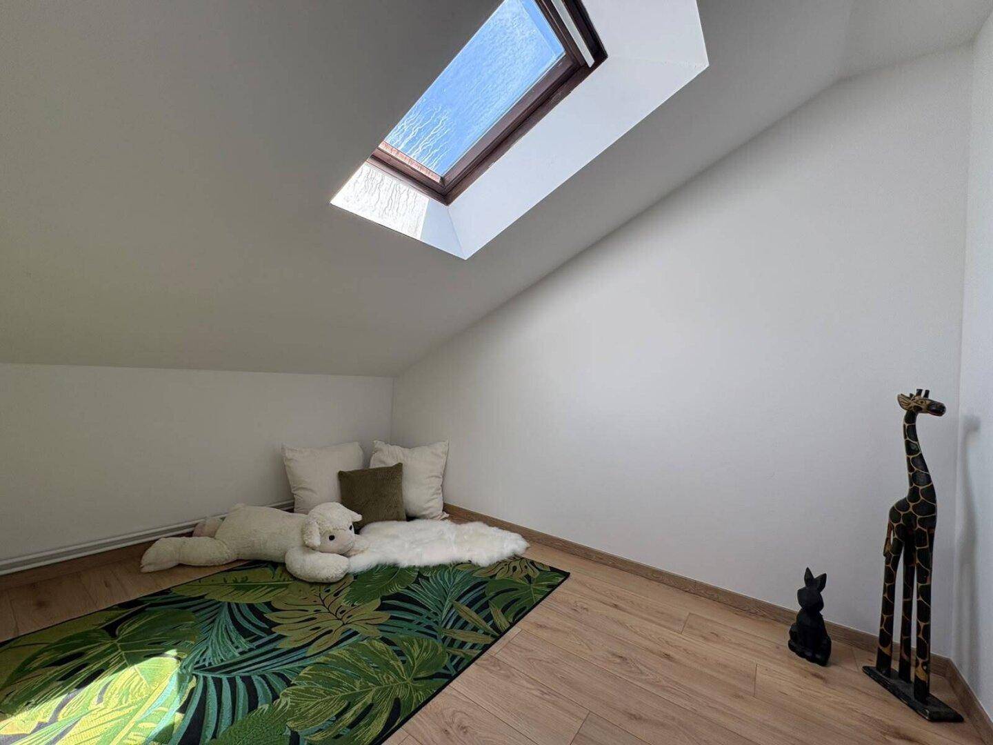 Gemütlicher Raum im Dachgeschoss mit Dachfenster und schräger Decke, ideal als Leseecke.
