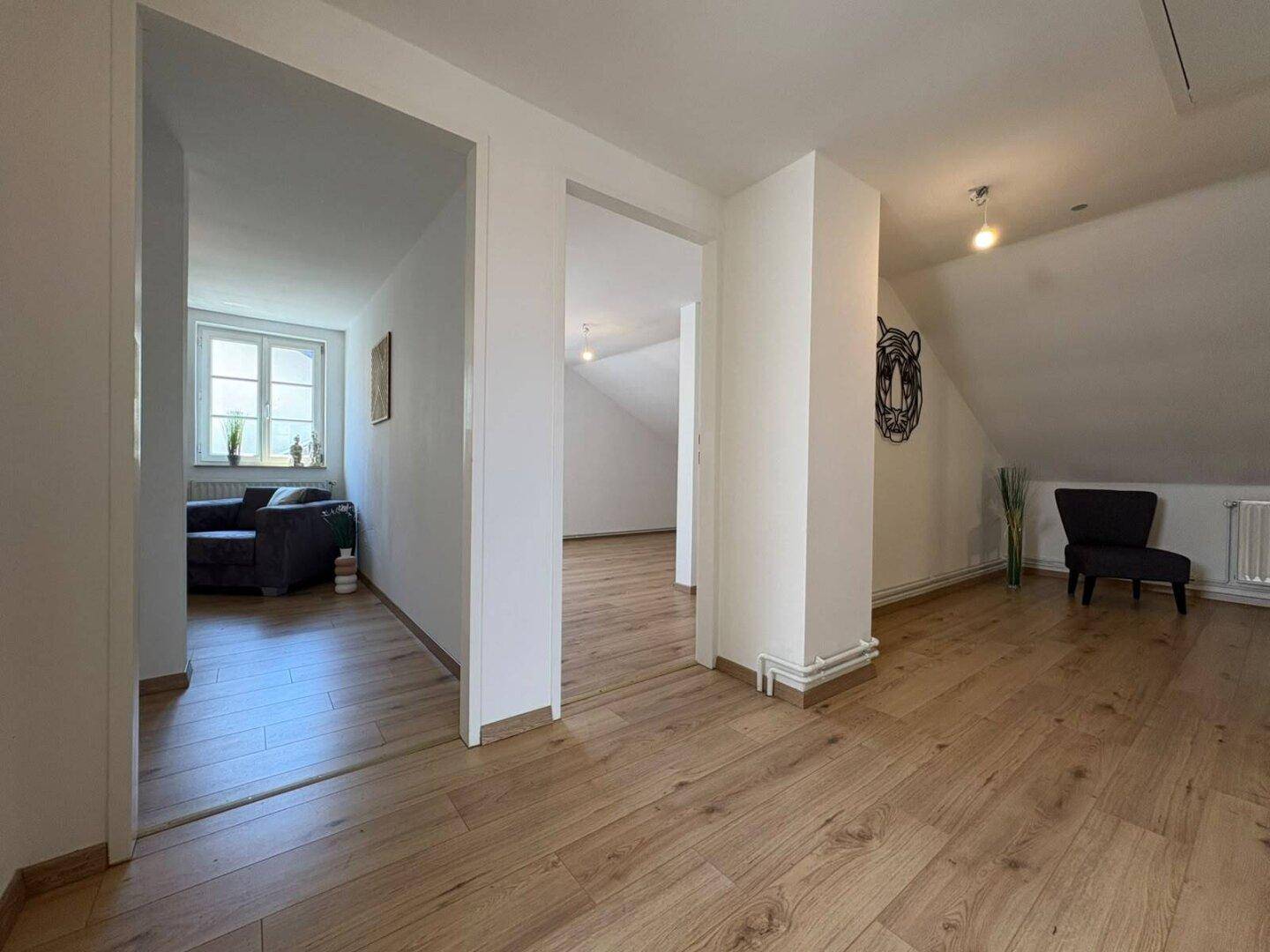 Offener Bereich im Dachgeschoss mit Holzboden, der zu verschiedenen Zimmern führt.