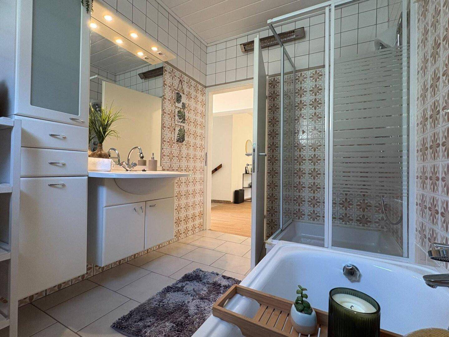 Badezimmer mit Waschtisch, Spiegel und gemusterten Fliesen, die den Charme der 80er Jahre widerspiegeln.