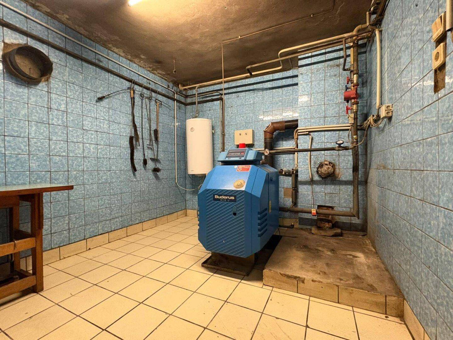 Funktionaler Heizungsraum mit Buderus Kessel, blauen Wandfliesen und gefliestem Boden.