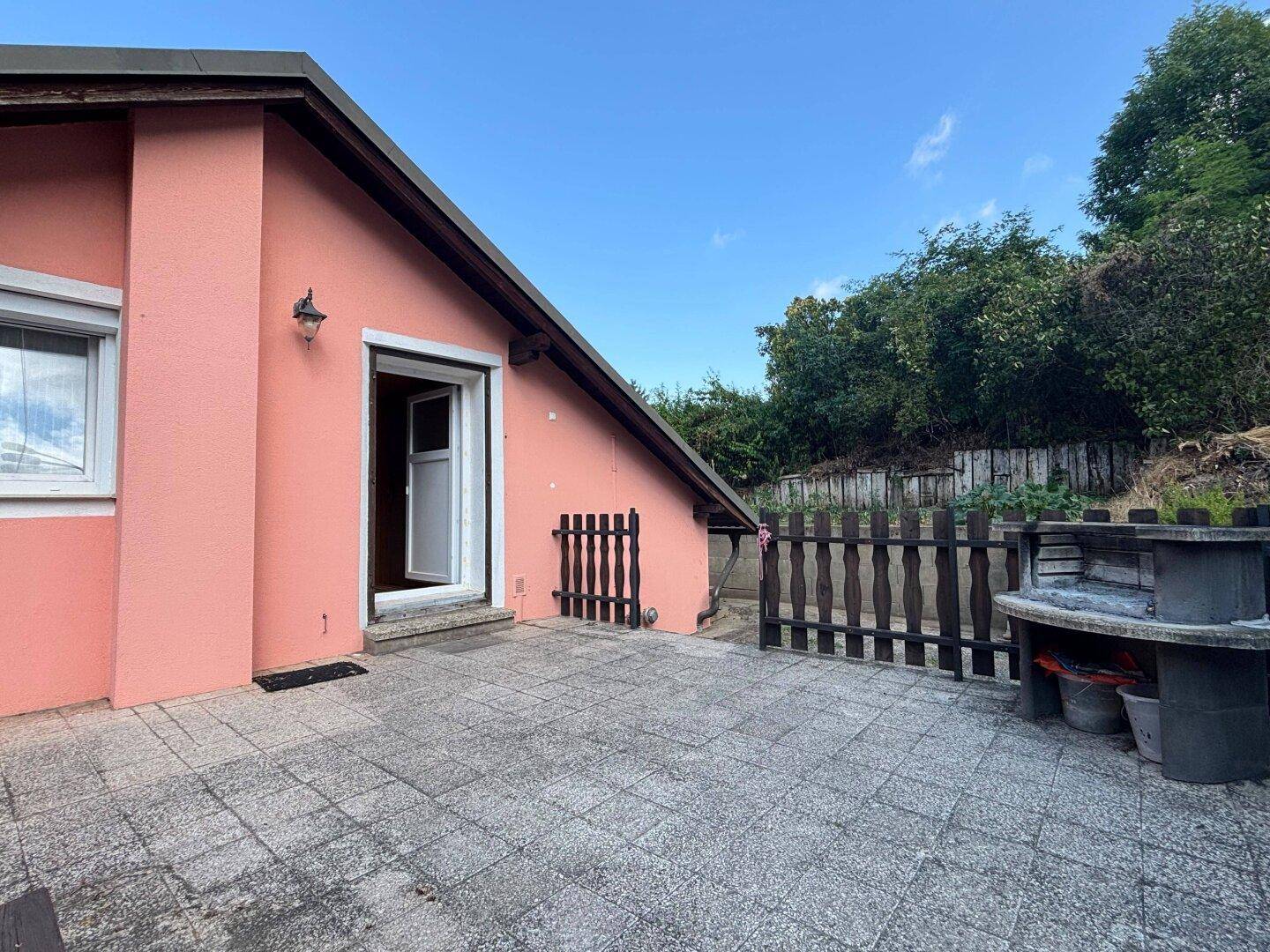 Grosse gepflasterte Terrasse mit Grillplatz und Zugang zum Haus.