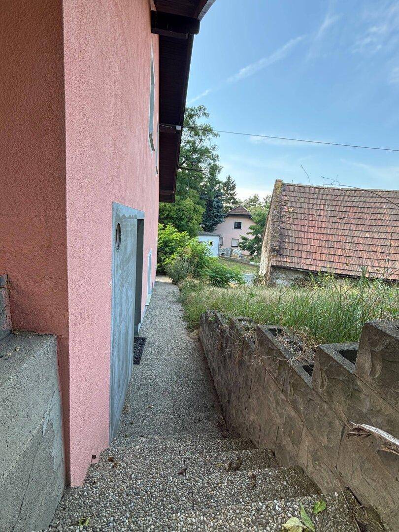 Seitlicher Zugang zum Haus mit Treppe und Blick auf die Nachbarschaft.