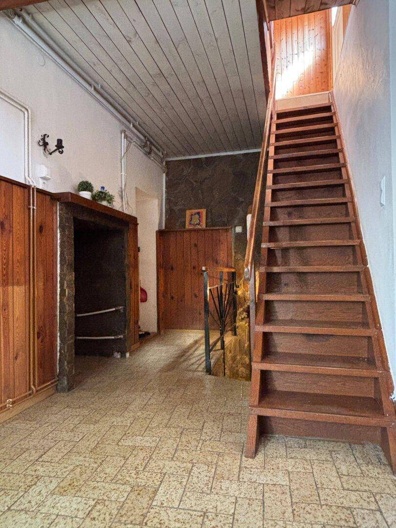 Eingangsbereich mit Holztreppe, gefliestem Boden und rustikalen Holzelementen.