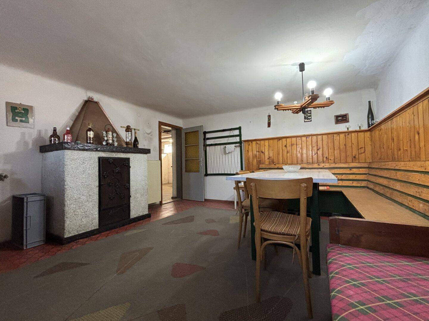 Gemütlicher Essbereich mit Kachelofen, Holzvertäfelung und rustikalen Möbeln.