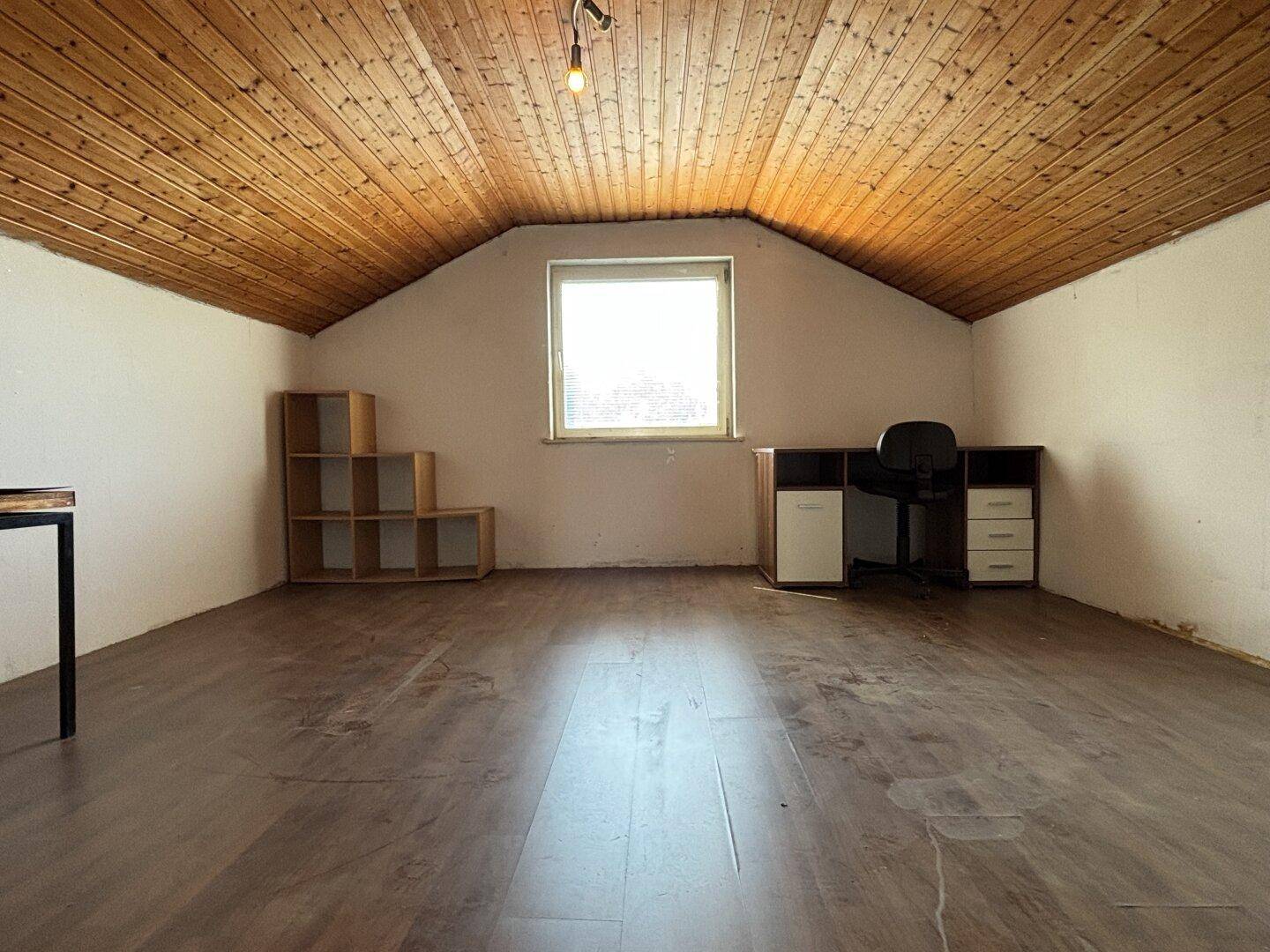 Helles Dachzimmer mit Holzdecke, Laminatboden und Fenster, ideal als Büro.