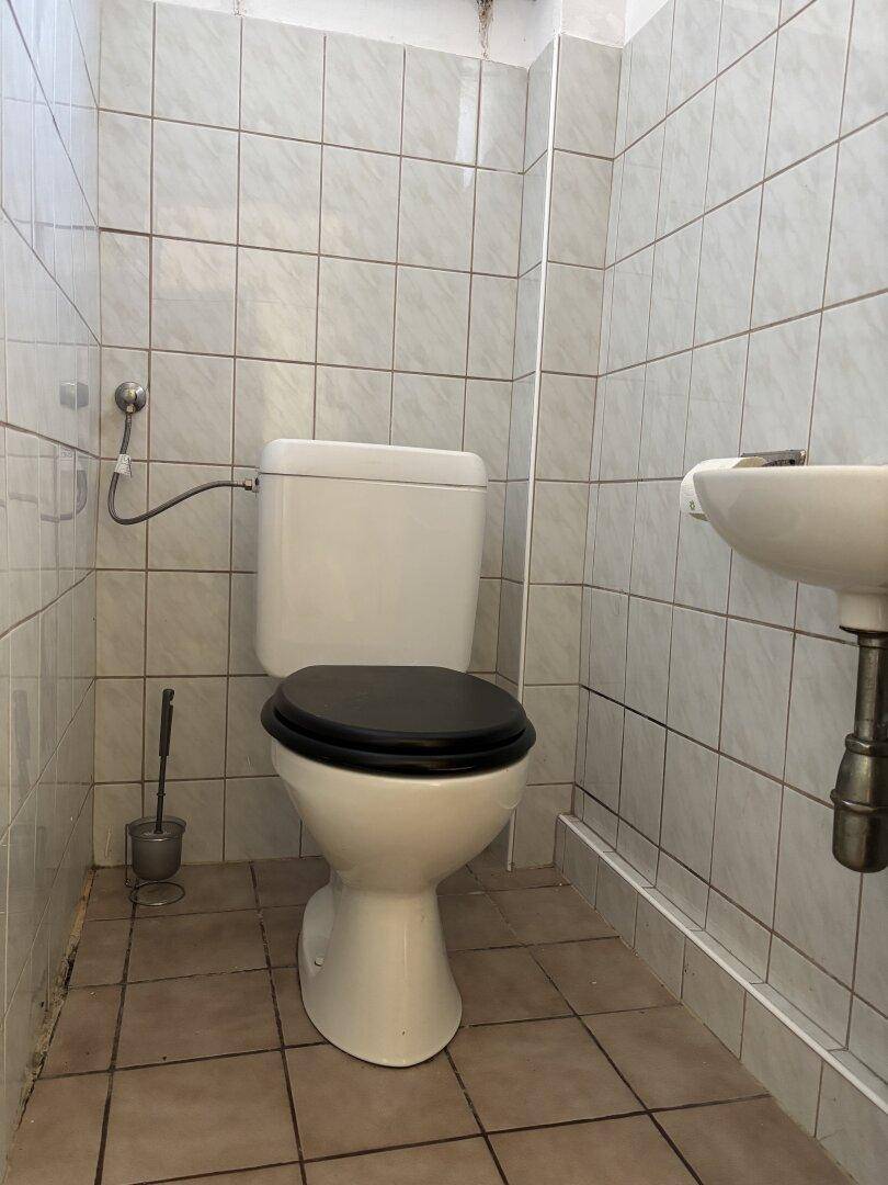 Kleines, gefliestes Gäste-WC mit Toilette und Handwaschbecken in hellem Design.