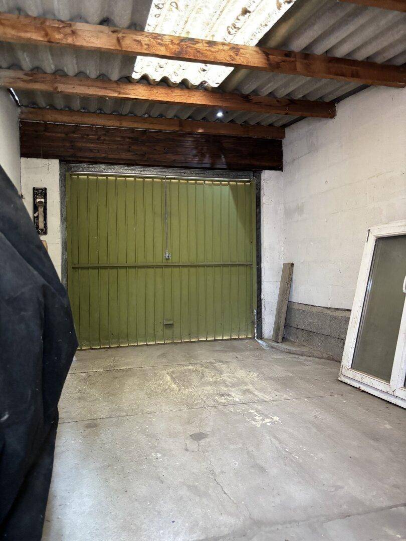 Geräumige Garage mit Schwingtor und Betonboden, bietet Platz für ein Fahrzeug.