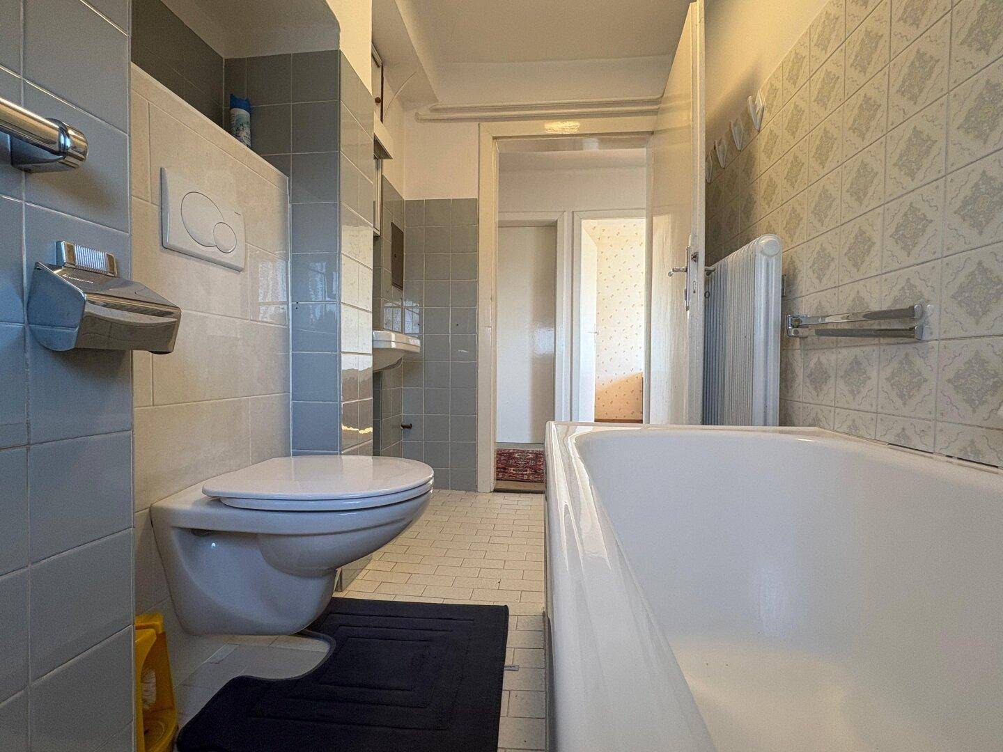 Badezimmer im Dachgeschoss mit Badewanne, Toilette und traditionellen Fliesen.