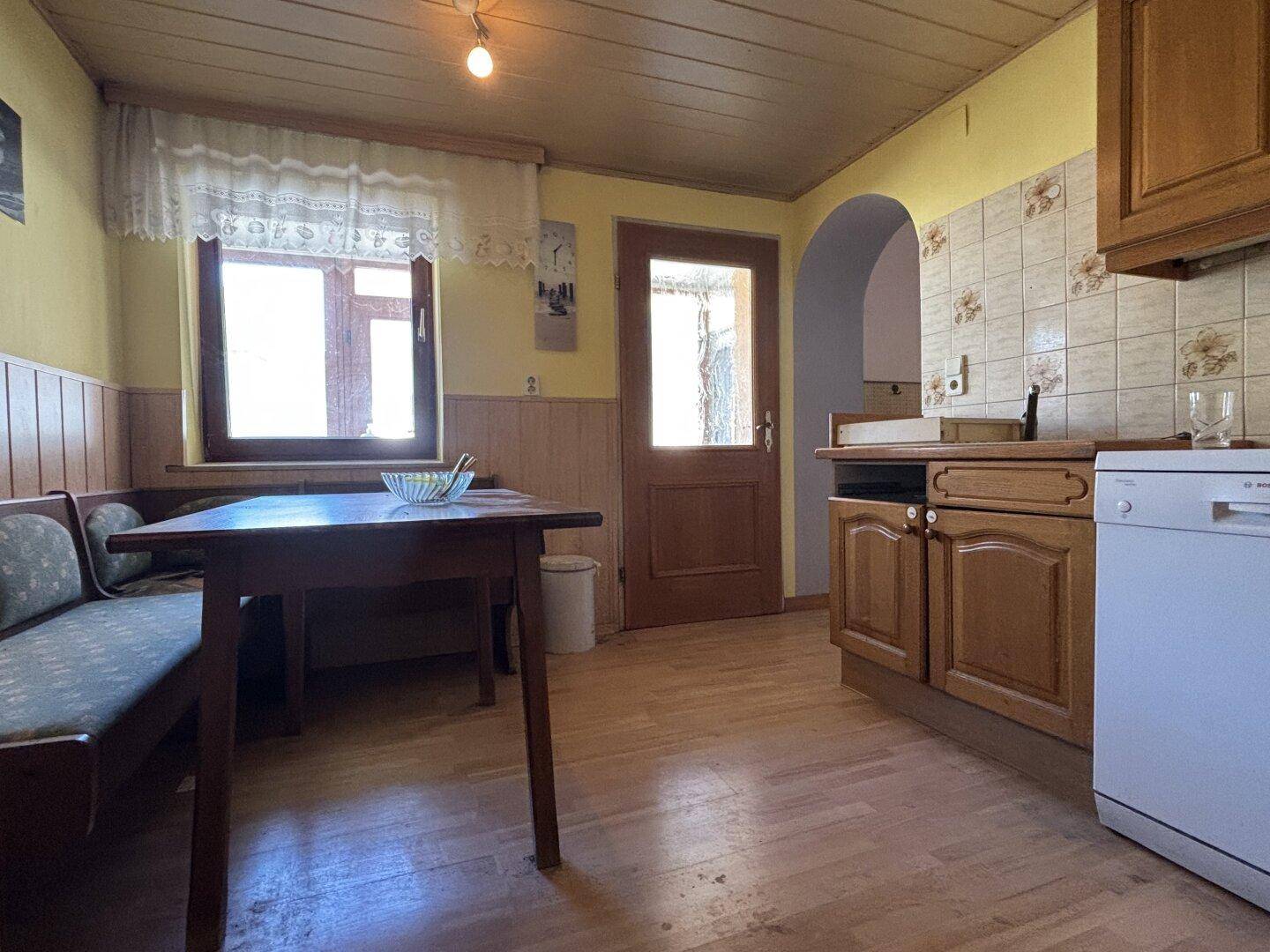 Gemütliche Wohnküche mit Holztisch, Eckbank und traditionellen Holzmöbeln.