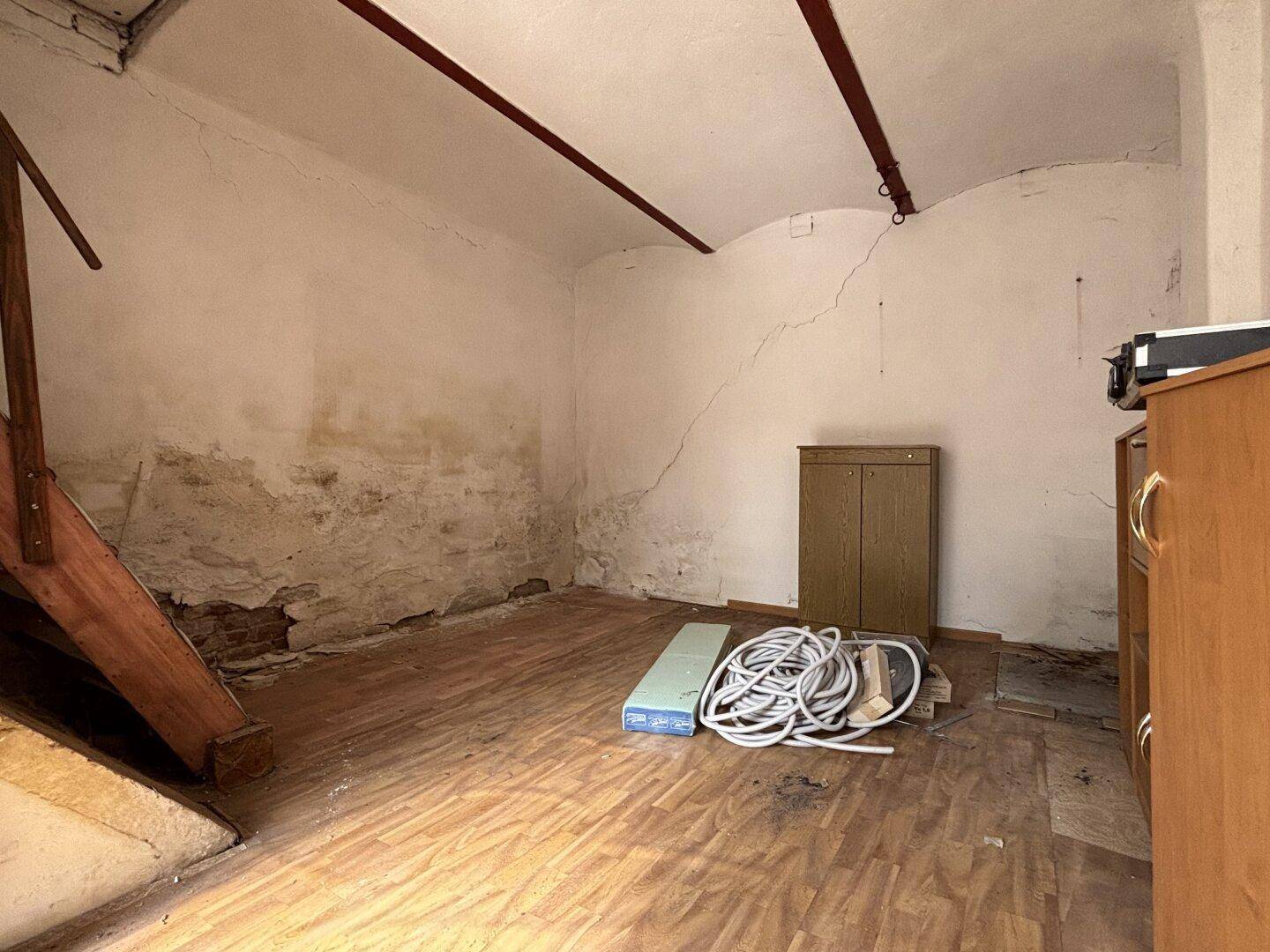 Geräumiger Dachboden mit Holzbalken und sichtbaren Spuren der Zeit, ideal für Ausbau.