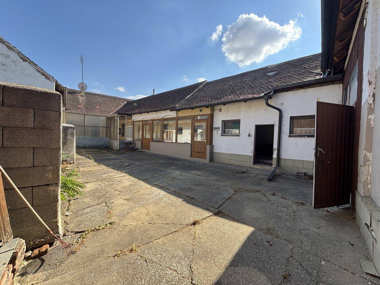 Hinterhof mit gepflastertem Bereich und Zugang zu mehreren Gebäudeteilen.