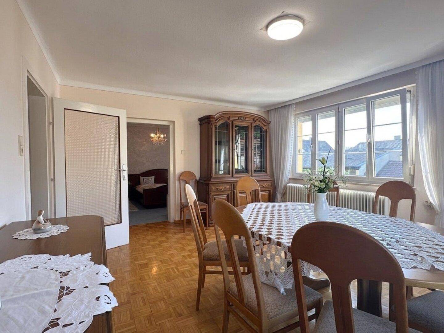 Helles Esszimmer mit traditionellen Möbeln, Parkettboden und Blick ins Grüne.
