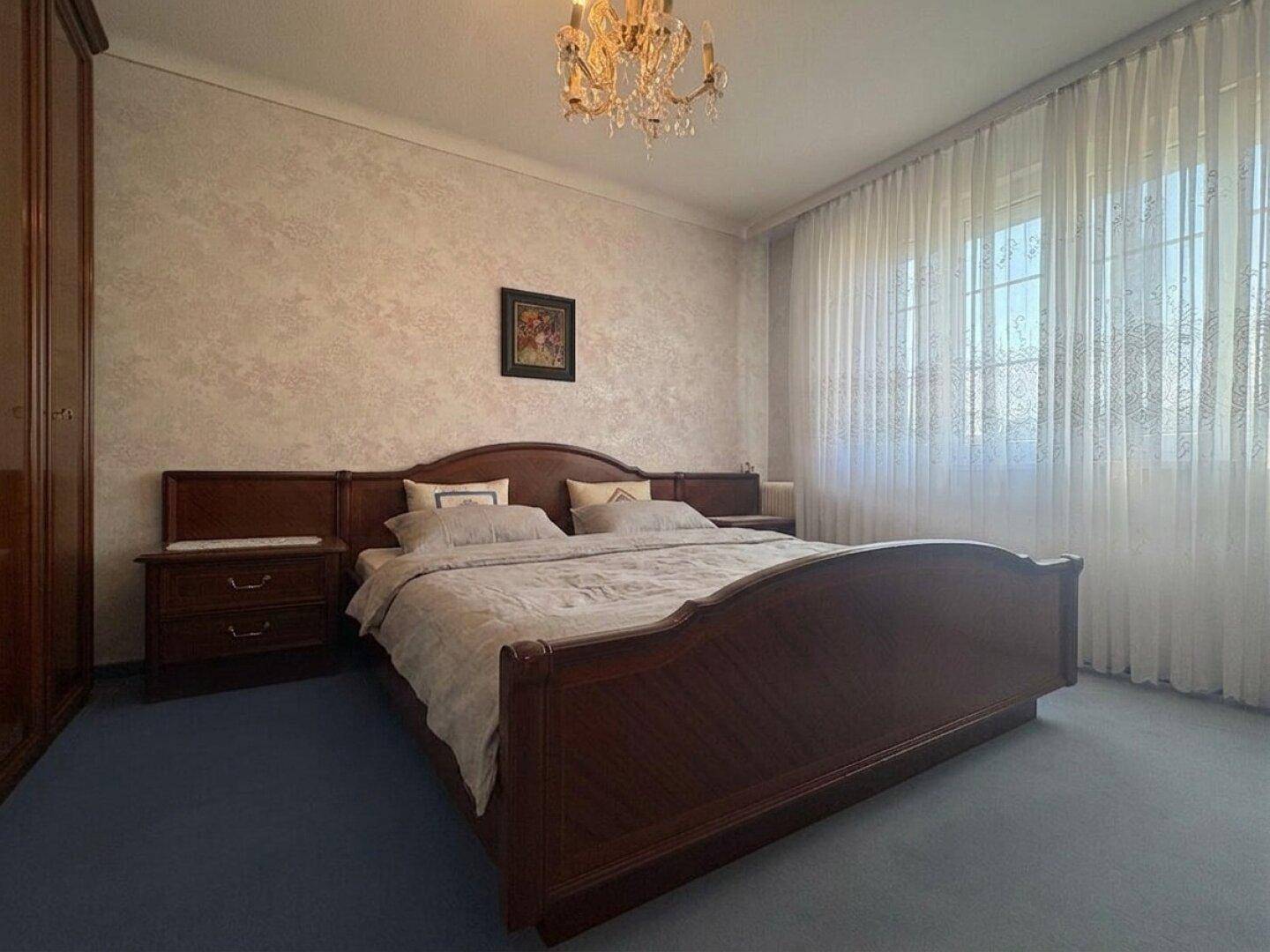 Schlafzimmer mit Doppelbett, Teppichboden und traditionellem Kronleuchter.