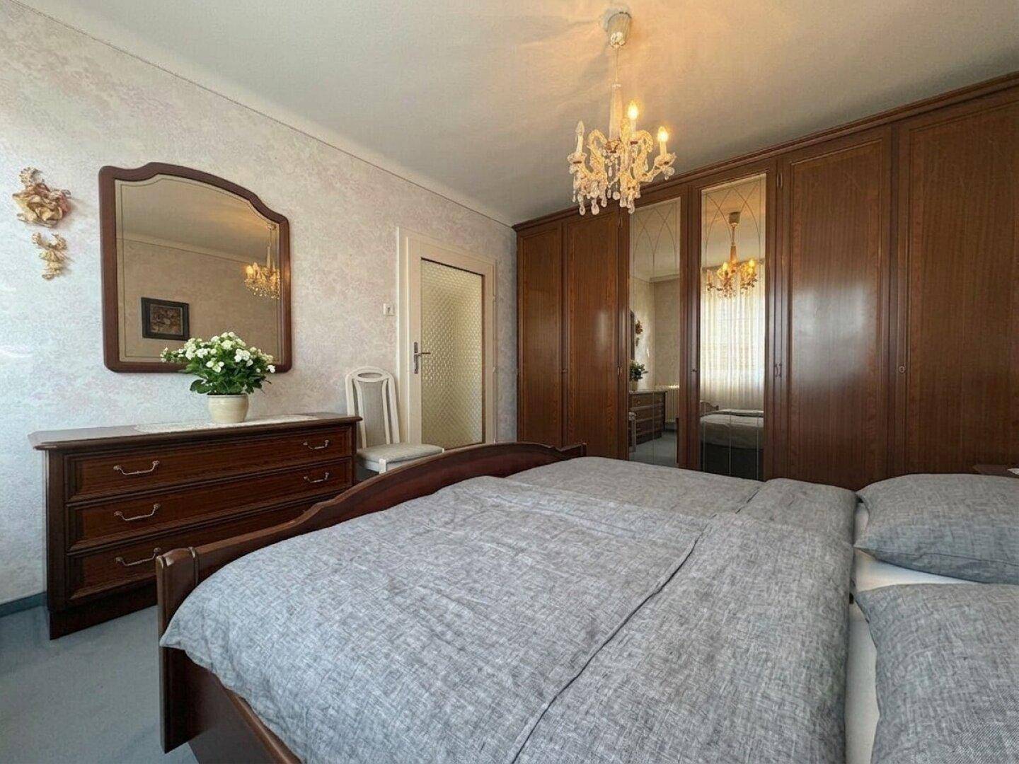 Schlafzimmer mit großem Kleiderschrank, Doppelbett und Spiegelkommode.