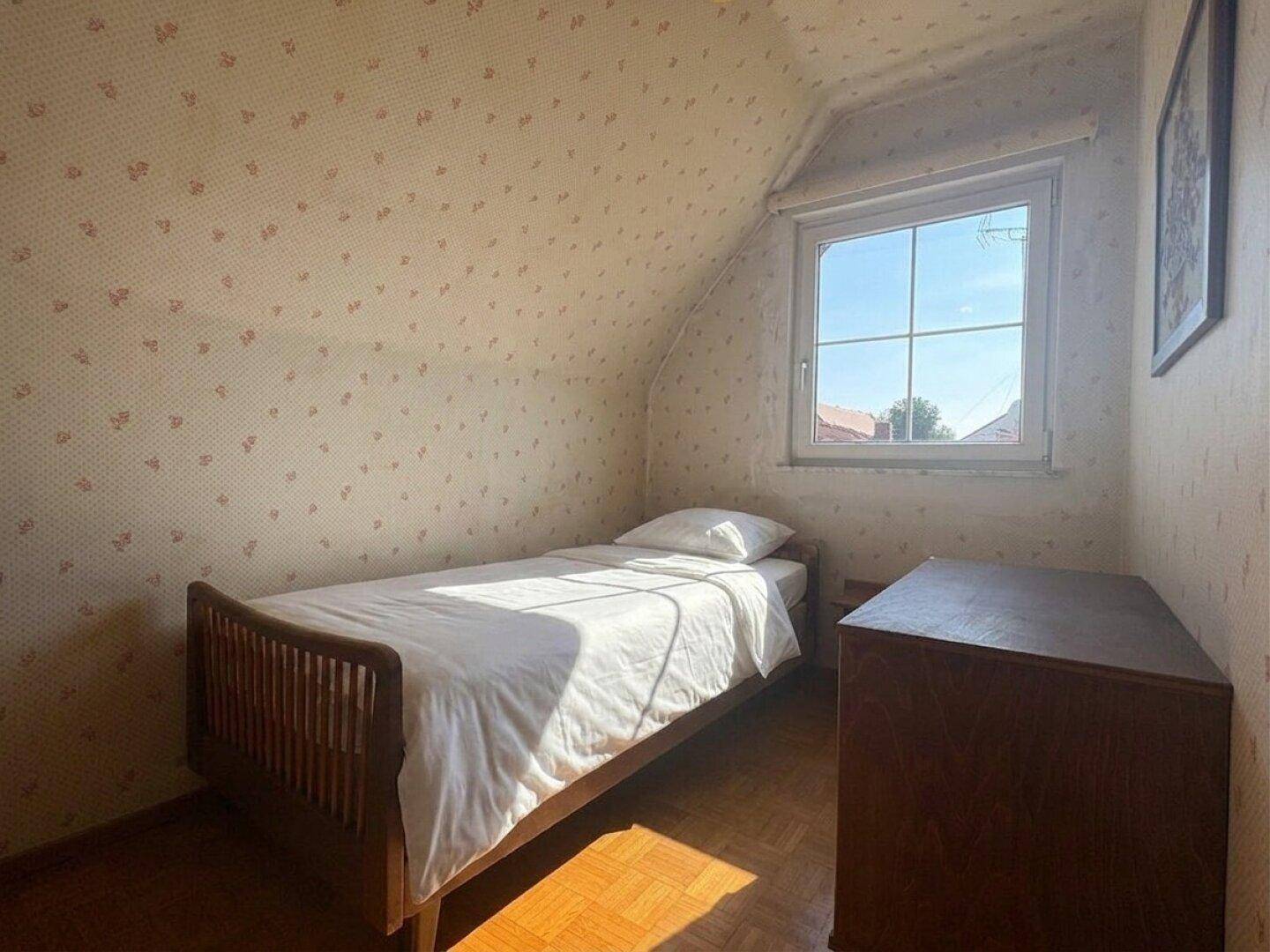 Gemütliches Schlafzimmer im Dachgeschoss mit Einzelbett, Holzboden und schräger Decke.