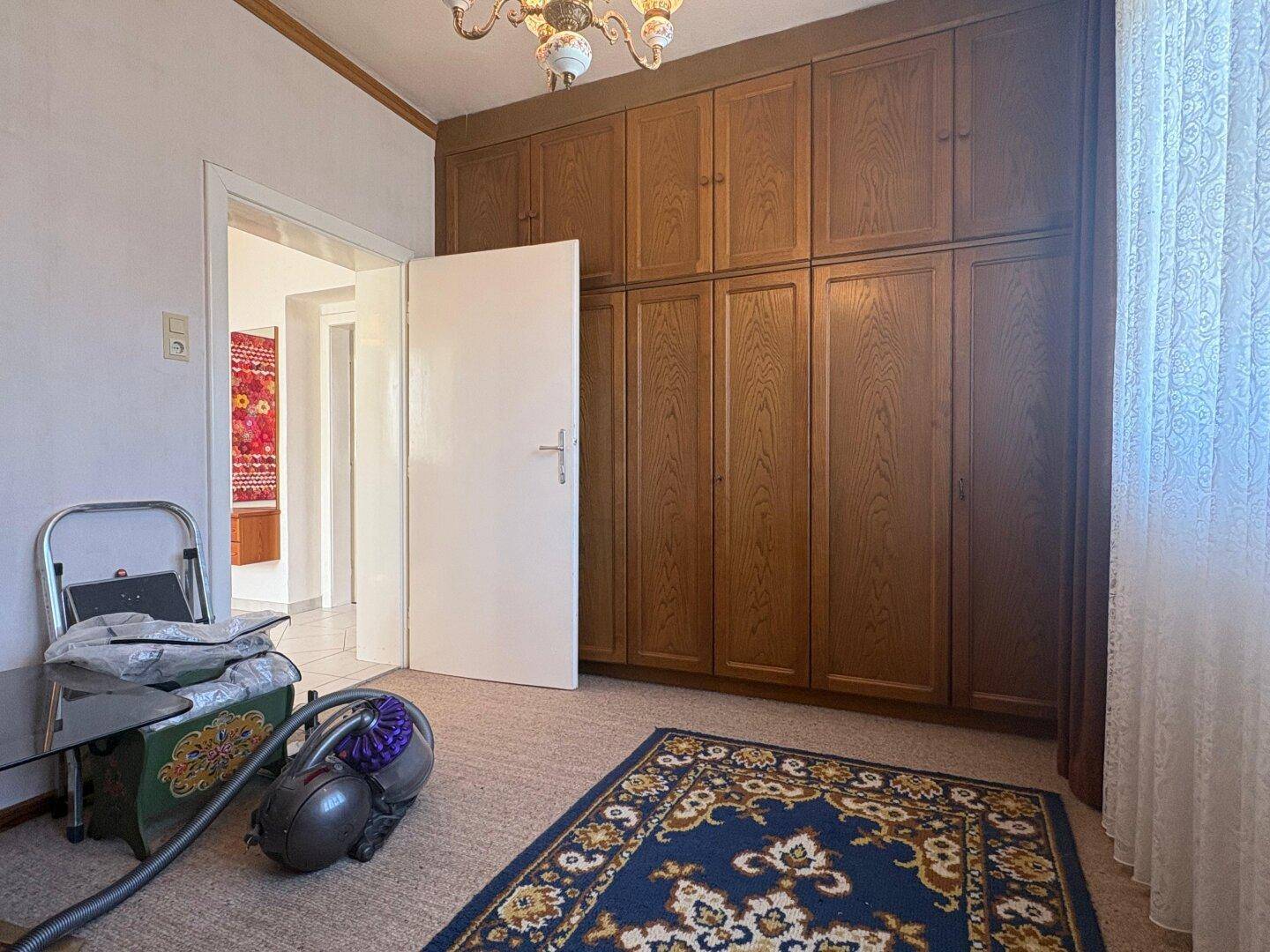 Schlafzimmer mit großen Einbauschränken aus Holz und Teppichboden.