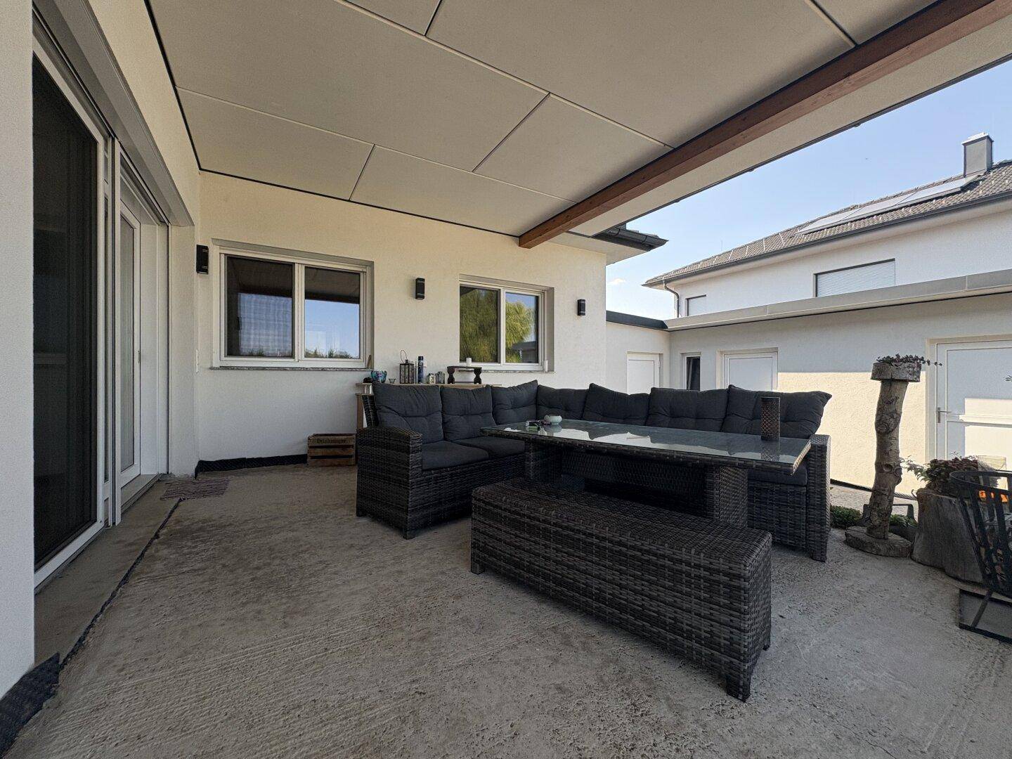 Überdachte Terrasse mit bequemen Loungemöbeln und Blick in den Garten.