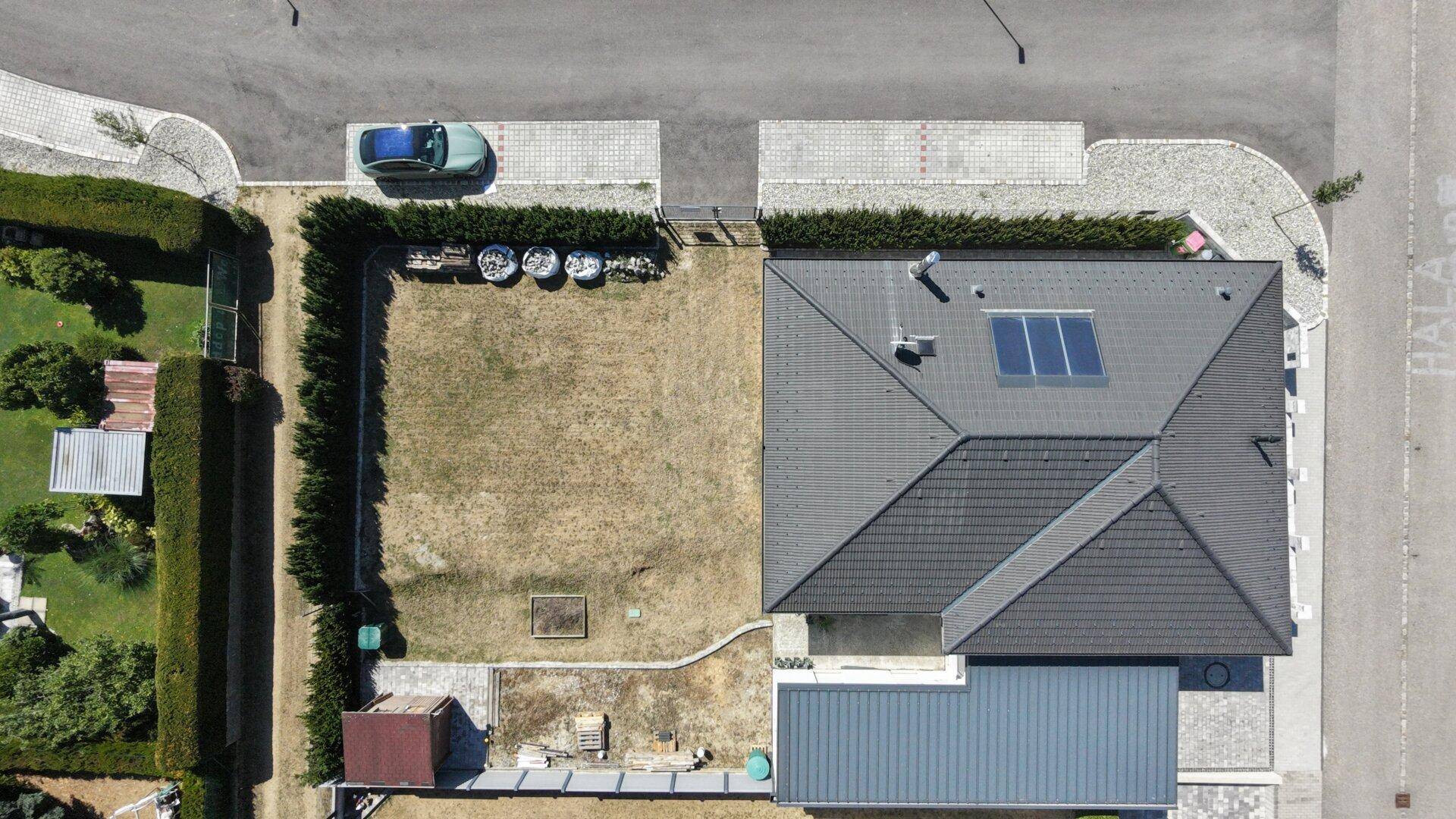 Draufsicht auf das Haus mit Garten, Dach und angrenzender Straße.