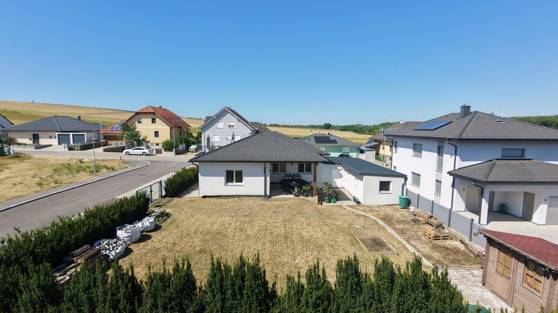 Luftaufnahme des Einfamilienhauses mit Gartenbereich und umliegender Landschaft.