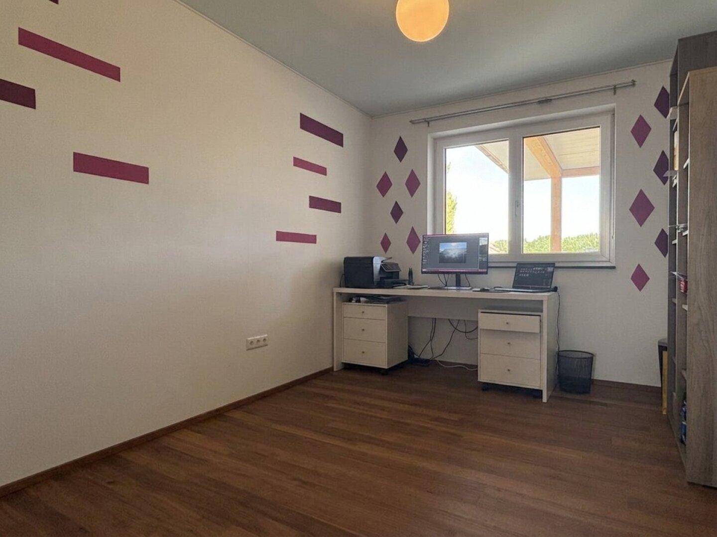Arbeitszimmer mit Holzboden, Schreibtisch und farbigen Wandakzenten.