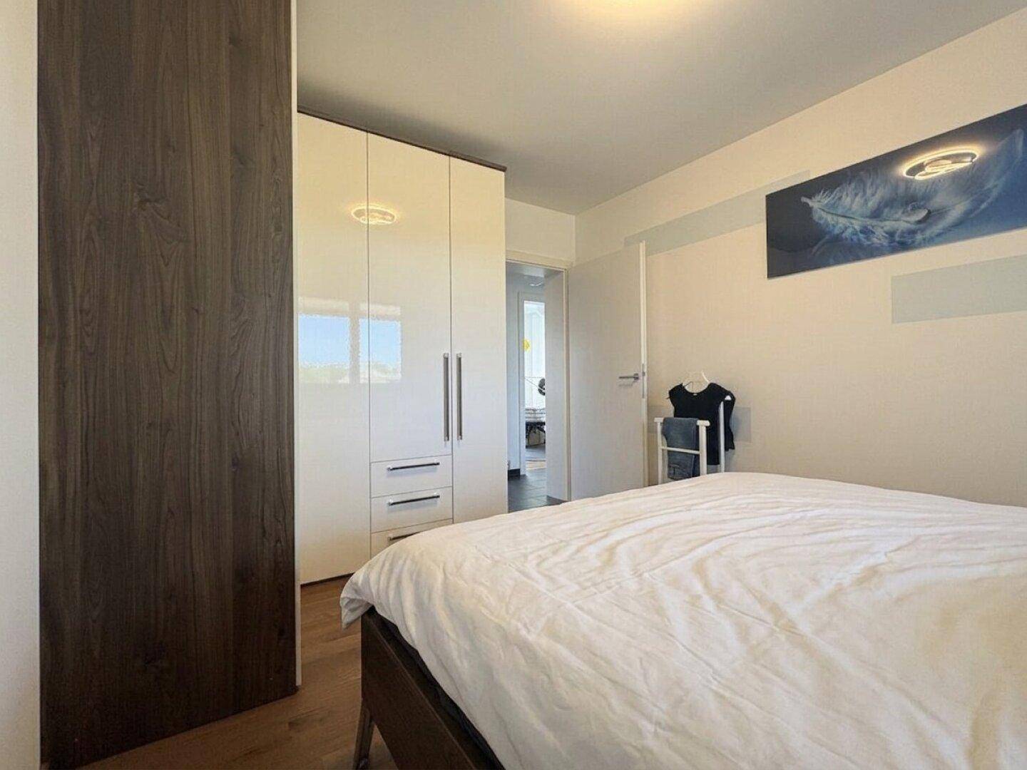 Schlafzimmer mit Holzboden, weißem Kleiderschrank und moderner Dekoration.
