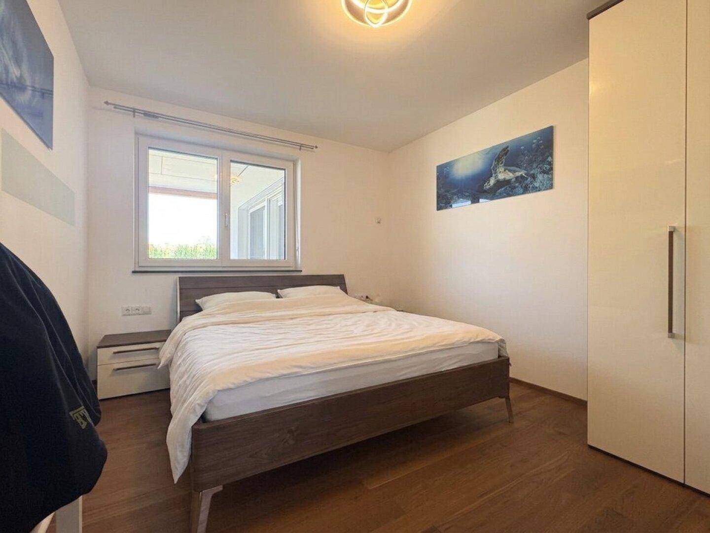Helles Schlafzimmer mit Holzbett, Nachttischen und Blick ins Grüne.