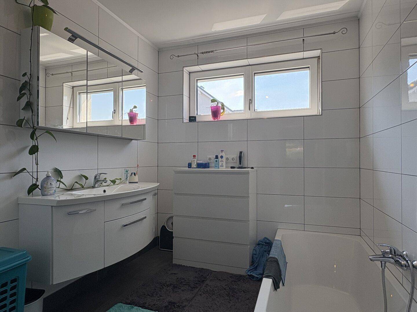 Modernes Badezimmer mit Badewanne, Waschtisch und Fenster.