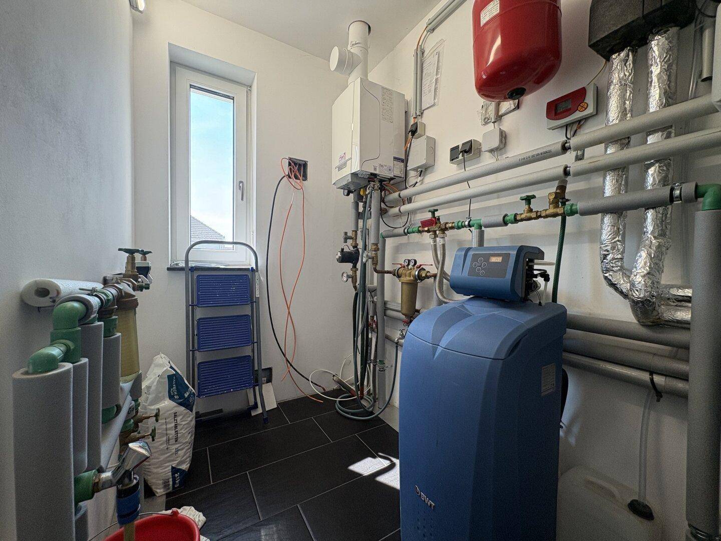 Technikraum mit Heizungsanlage, Warmwasserspeicher und Wasseraufbereitungssystem.