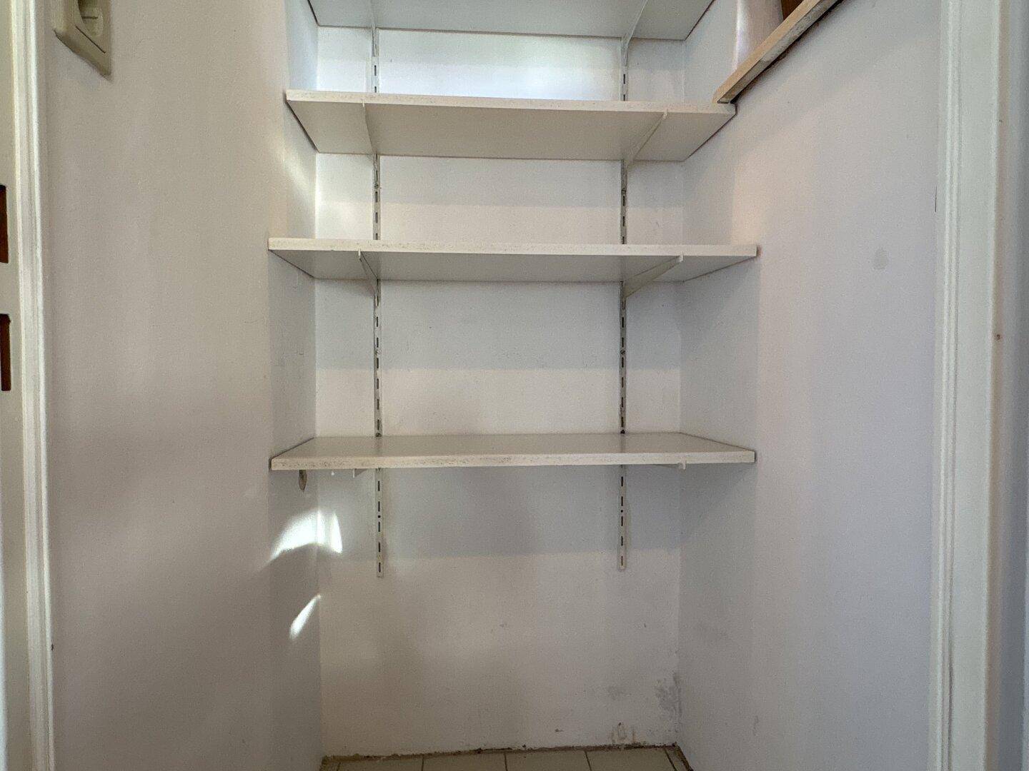 Praktischer Abstellraum mit weißen Regalen an der Wand, ideal für zusätzlichen Stauraum.