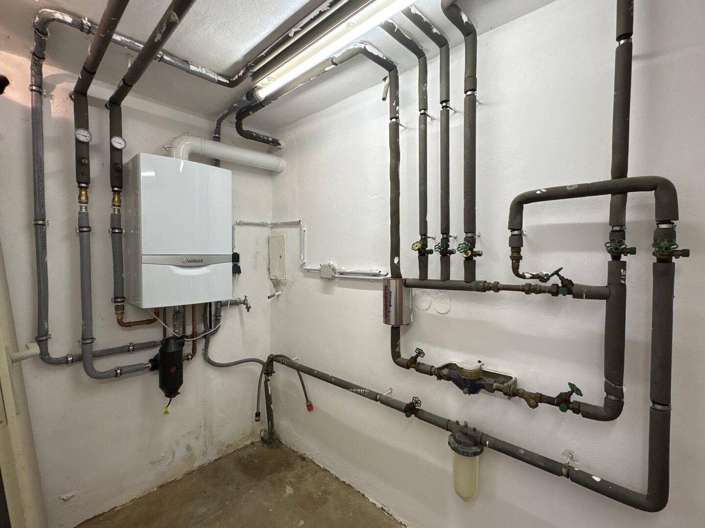 Technikraum mit Heizungsanlage und umfangreicher Rohrinstallation, gut zugänglich und funktional.