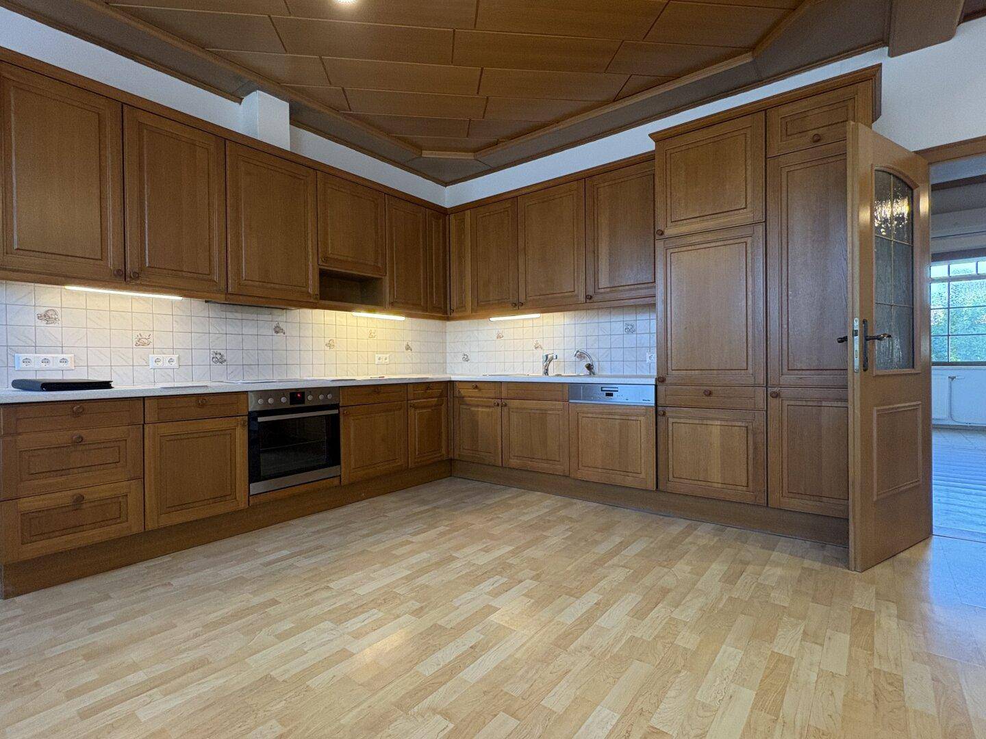 Traditionelle Holzküche mit Einbauschränken, Backofen und Spülmaschine, bereit zur Nutzung.