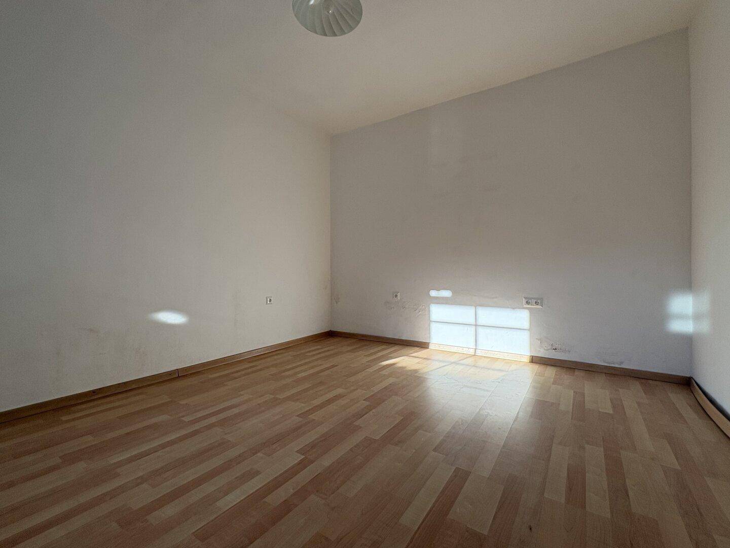 Leerer Raum mit Holzboden und weißen Wänden, der auf eine neue Nutzung wartet.