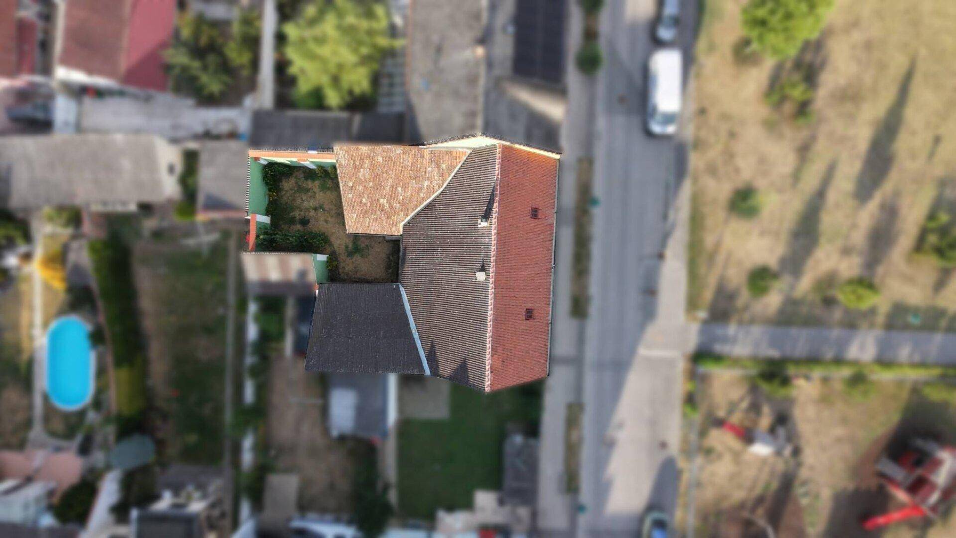 Luftaufnahme eines Wohnhauses mit Satteldach, umgeben von Gärten und der Nachbarschaft.